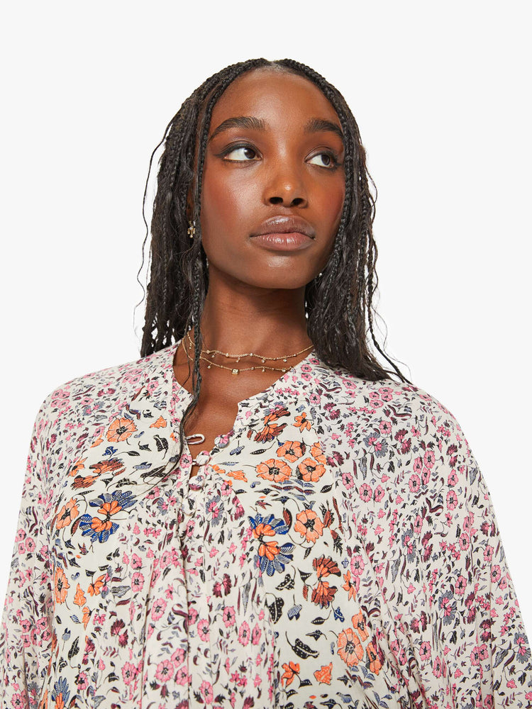 Close up view of a woman in white with a multi-color floral print, this maxi dress is designed with voluminous sleeves and has an A-line cut for a loose, breezy feel.