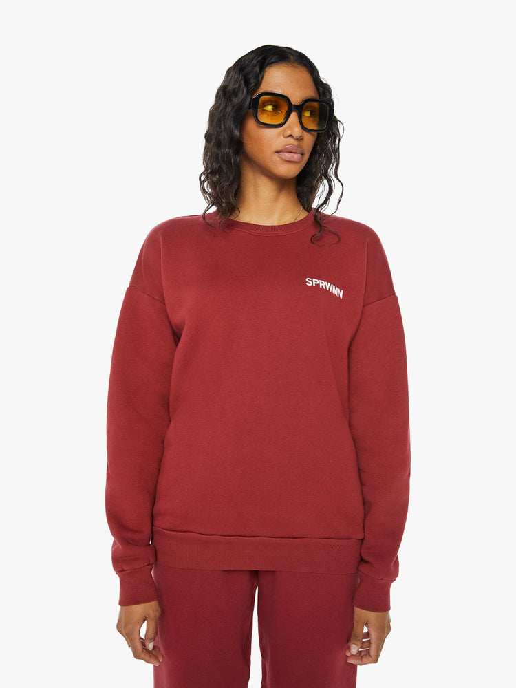 Front view of a woman crewneck sweatshirt with the brands logo on the front in crimson red hue.