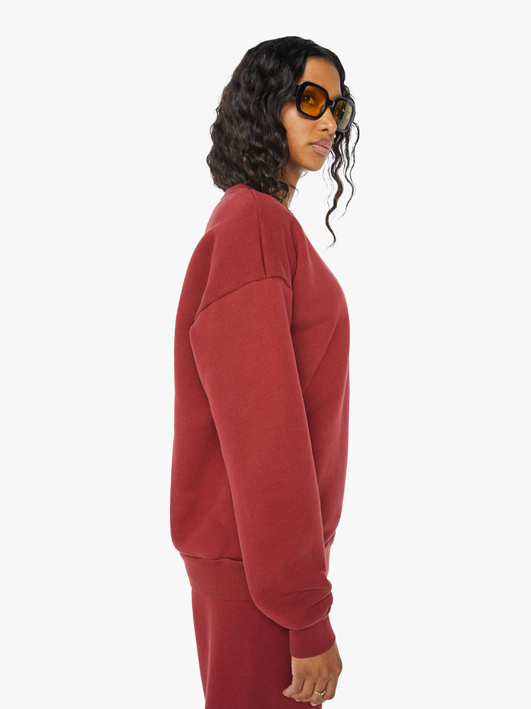Side view of a woman crewneck sweatshirt with the brands logo on the front in crimson red hue.