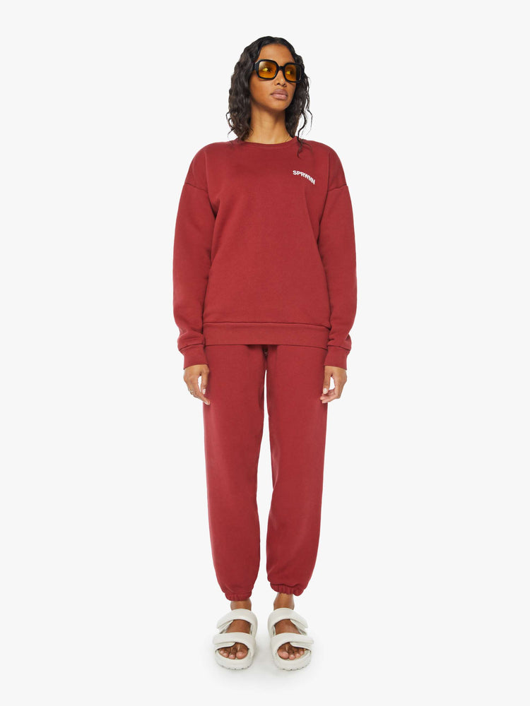 Full body view of a woman crewneck sweatshirt with the brands logo on the front in crimson red hue.