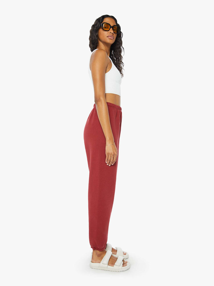 Side view of a woman crimson red sweatpants with an elastic waist and cuffs for a loose, comfortable fit.