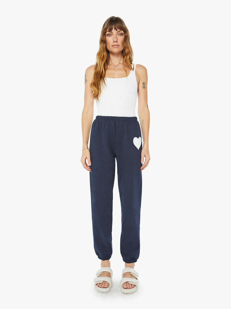 Front view of a woman navy with a white heart on the hip sweatpants with an elastic waist and cuffs for a loose, comfortable fit.