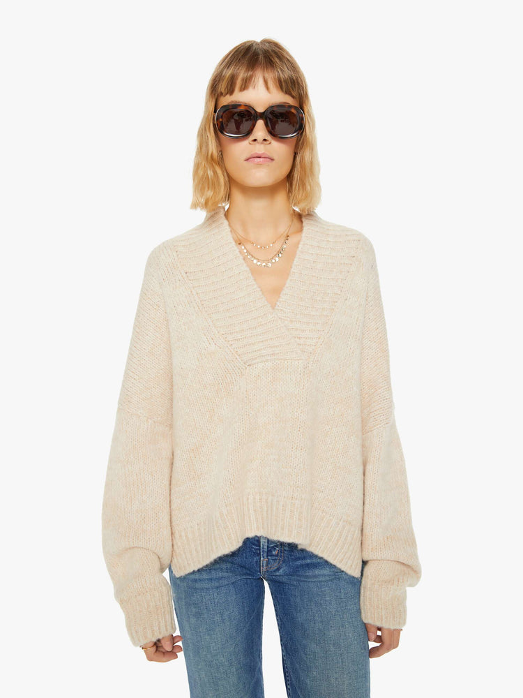 Front view of a woman marbled cream hue deep V-neck, long sleeves, ribbed hems and a loose fit sweater. 