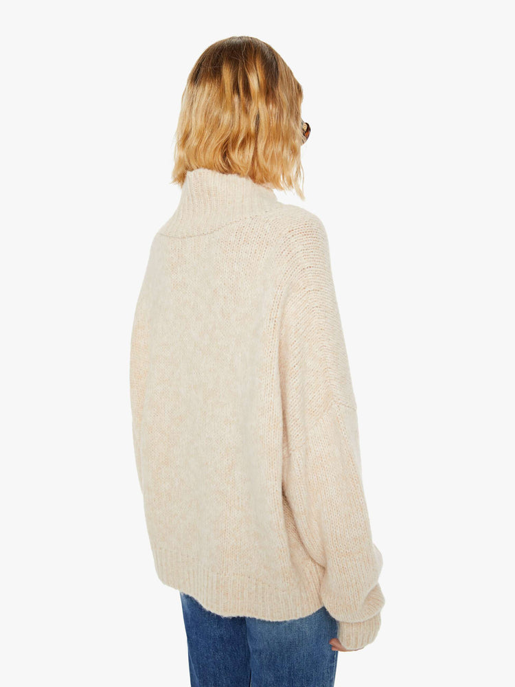 Back view of a woman marbled cream hue deep V-neck, long sleeves, ribbed hems and a loose fit sweater.