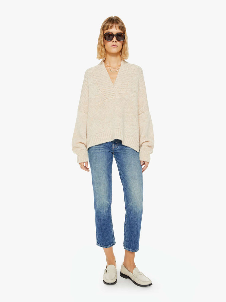 Full body view of a woman marbled cream hue deep V-neck, long sleeves, ribbed hems and a loose fit sweater.