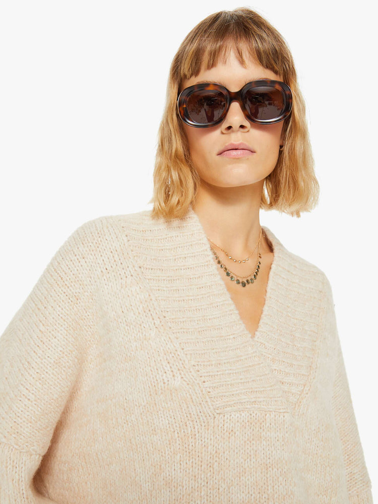 Close up view of a woman marbled cream hue deep V-neck, long sleeves, ribbed hems and a loose fit sweater.