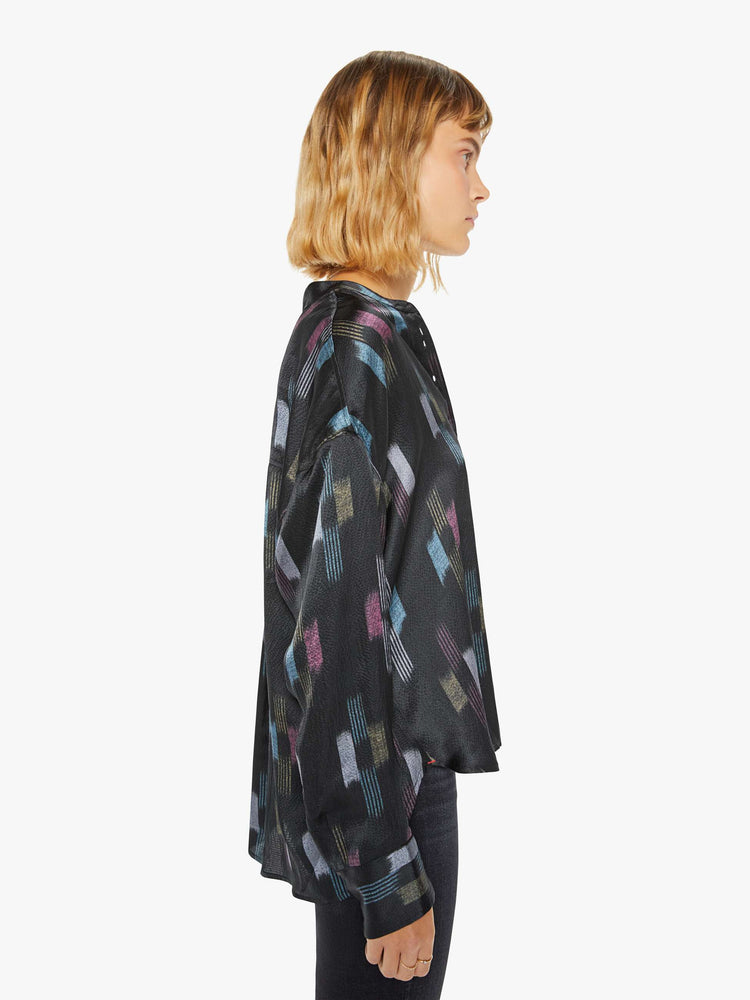 Side view of a woman black shirt with a cool toned graphic print with drop shoulders, long balloon sleeves, a slightly curved hem and buttons down the front.
