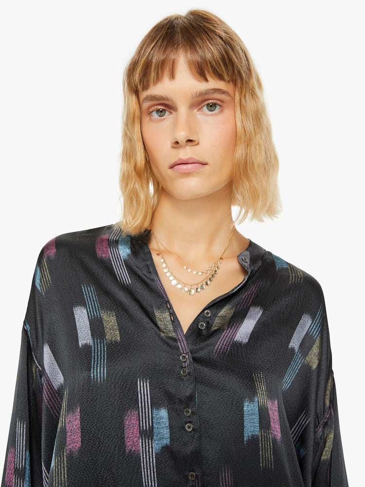 Close up view of a woman black shirt with a cool toned graphic print with drop shoulders, long balloon sleeves, a slightly curved hem and buttons down the front.