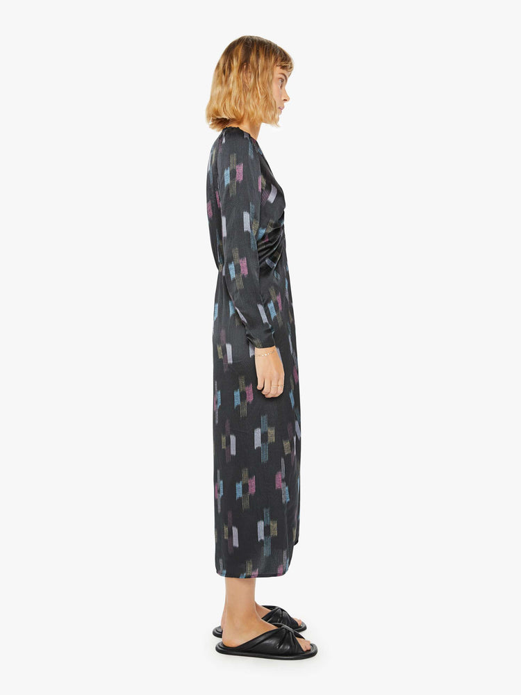 Side view of a womans black dress with cool toned graphic print with deep V-neck, gathered bodice, long sleeves and a calf-length hem.