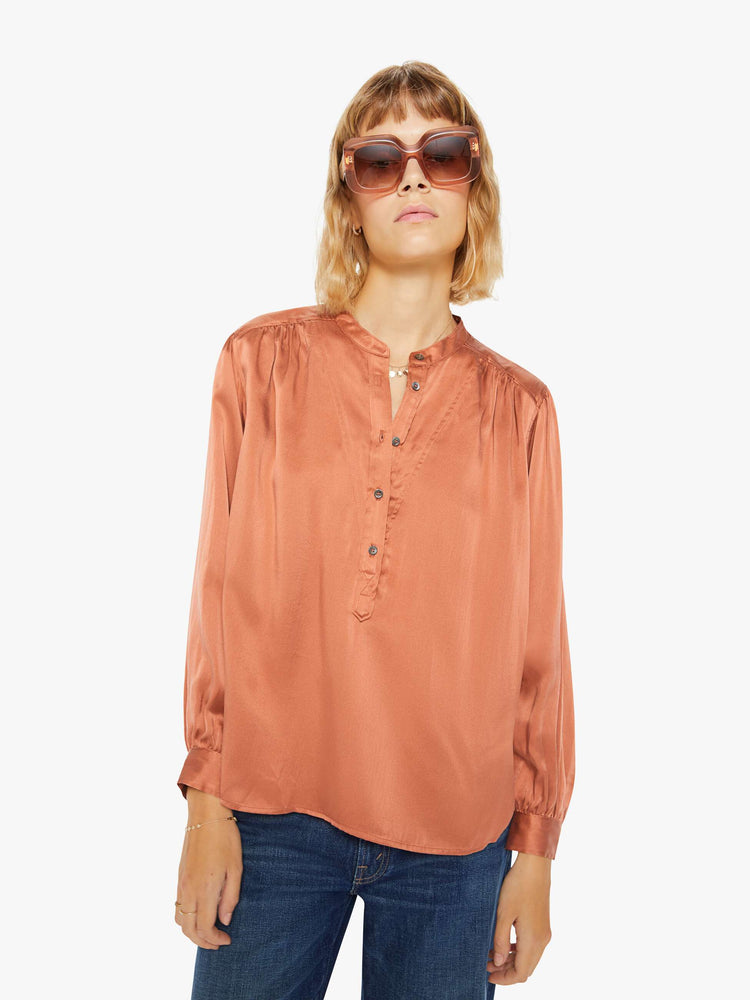 Front view of a woman buttoned V-neck, long balloon sleeves and a flowy fit long sleeve in a burnt orange hue.