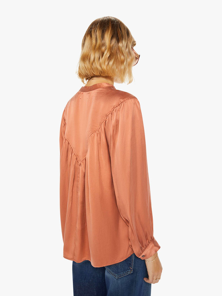 Back view of a woman buttoned V-neck, long balloon sleeves and a flowy fit long sleeve in a burnt orange hue.