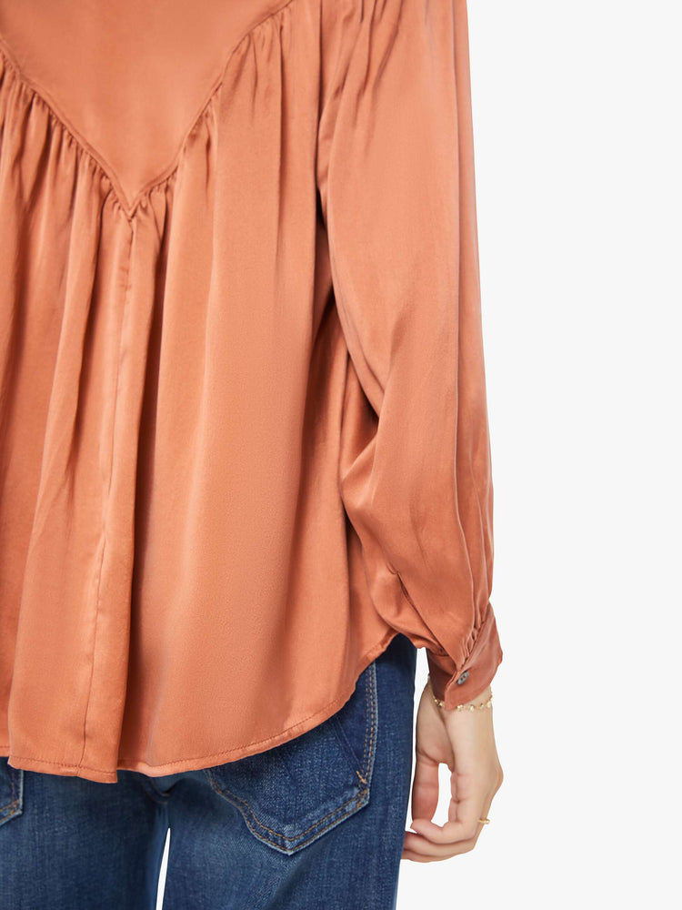 Detail view of a woman buttoned V-neck, long balloon sleeves and a flowy fit long sleeve in a burnt orange hue.