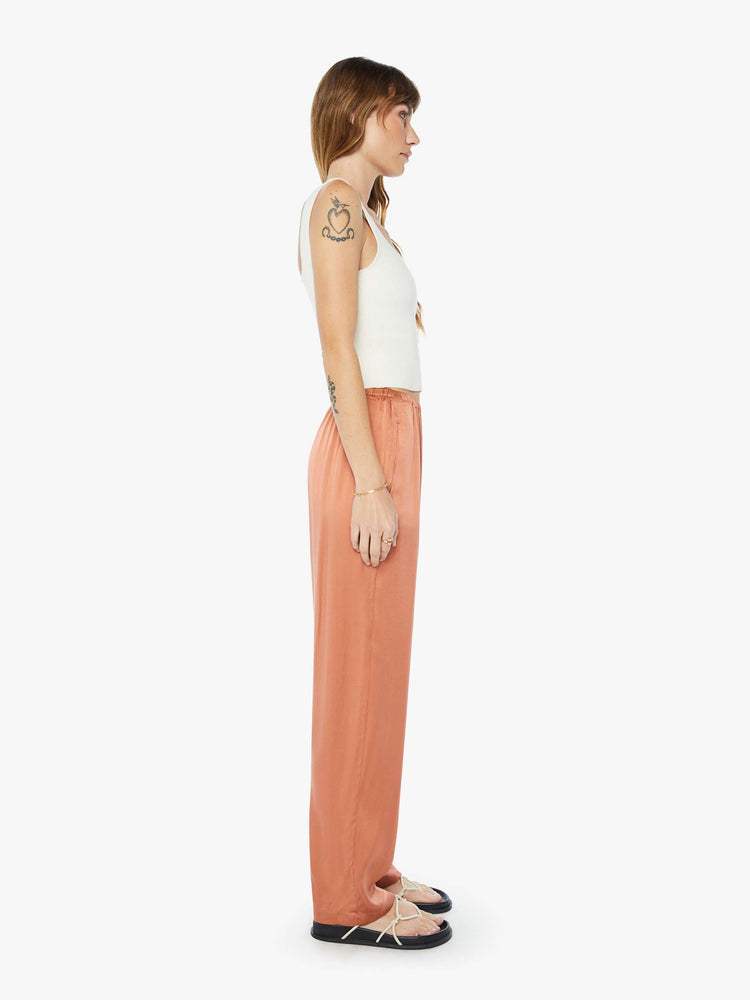 Side  view of woman burnt orange high rise, elastic waist and a loose, flowy fit pant.