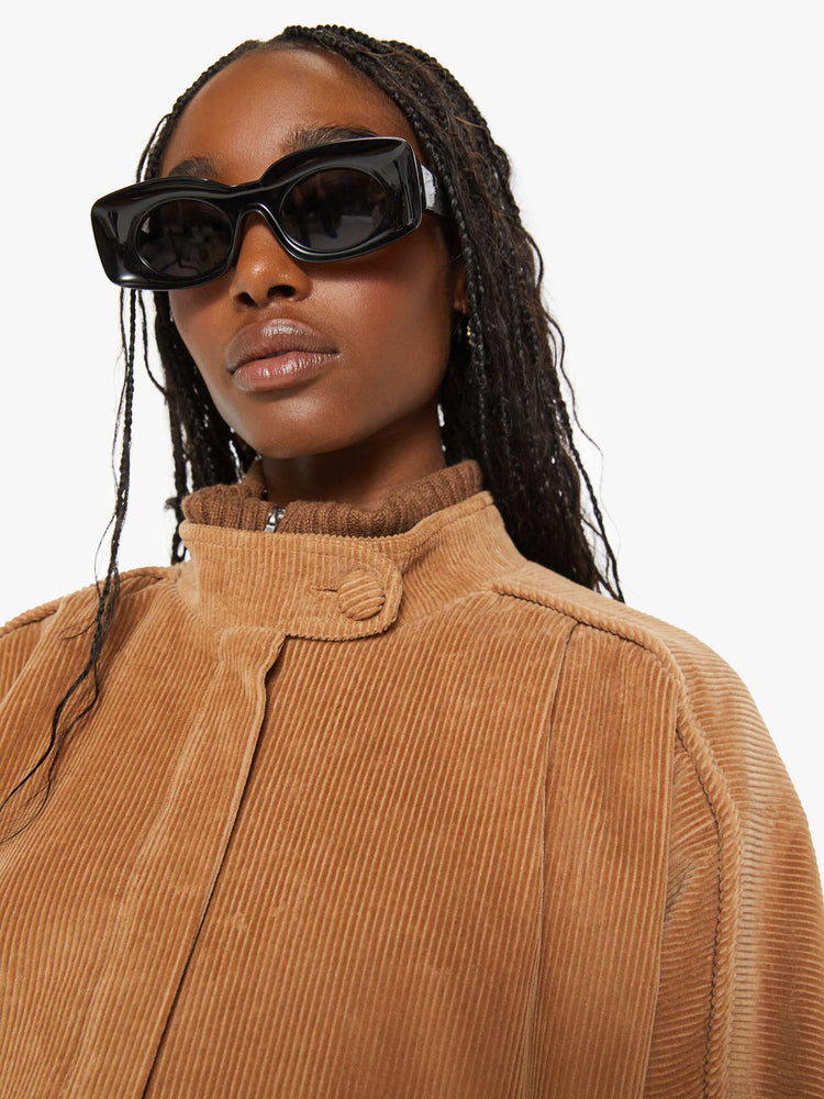 Close up view of a woman brown stacked collar, slit pockets, ribbed hems and a boxy fit coat.