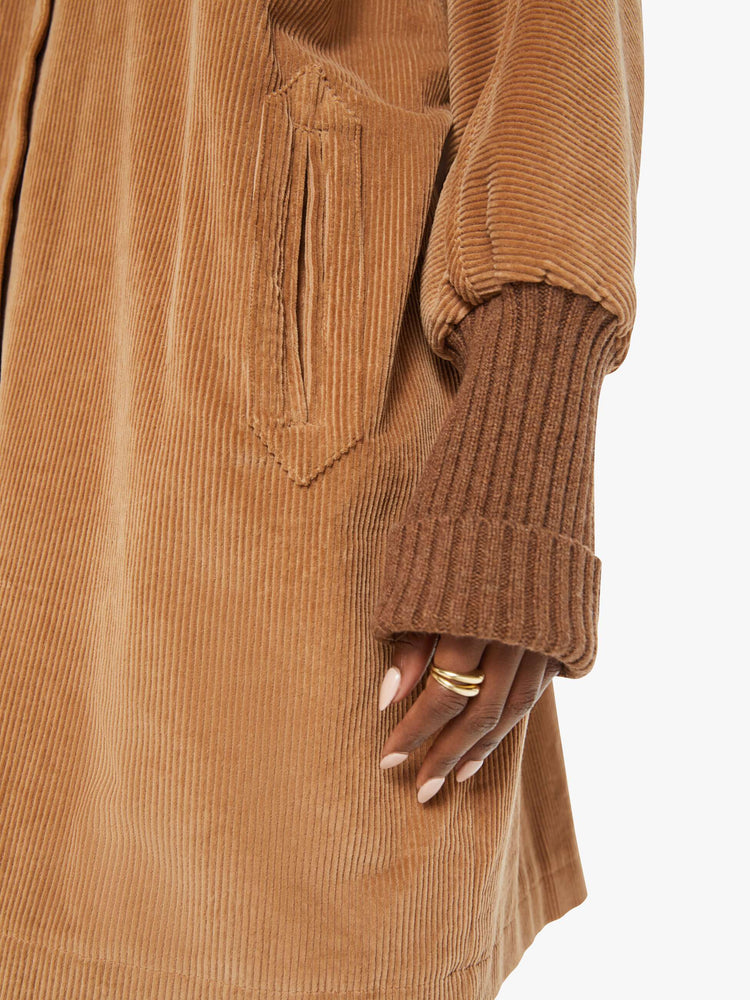 Detail view of a woman brown stacked collar, slit pockets, ribbed hems and a boxy fit coat.