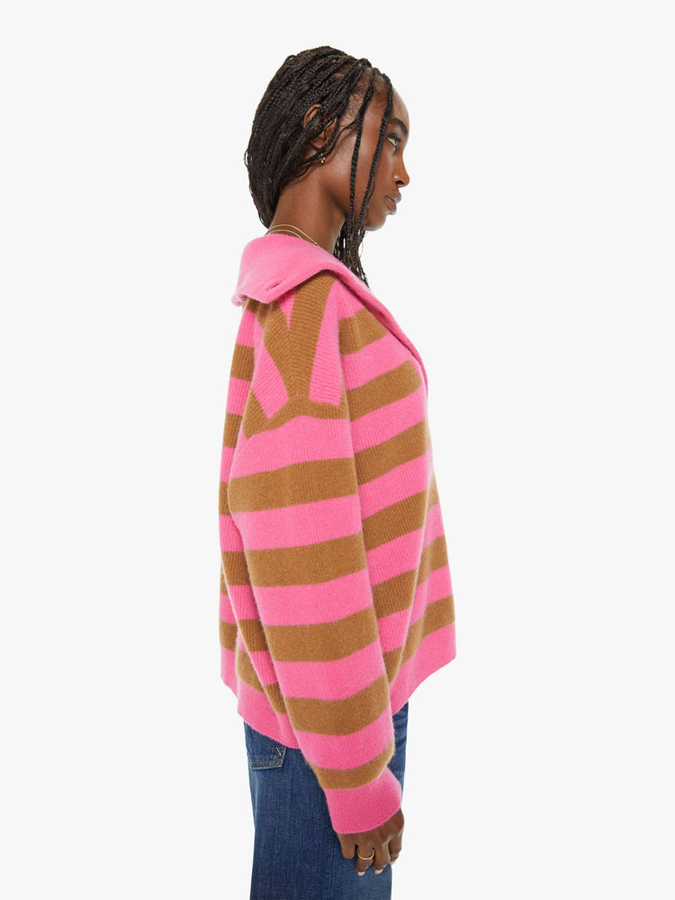 Side view of a woman oversized collar, buttoned V-neck, long balloon sleeves and a loose fit sweater in a hot pink and brown stripe pattern.
