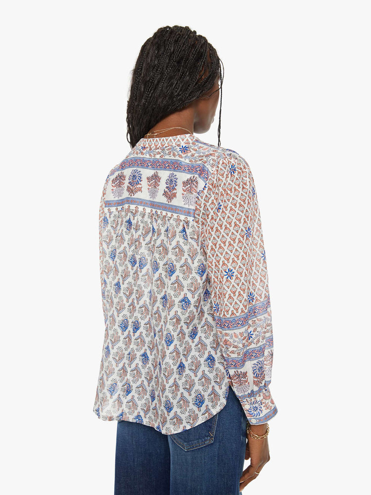 Back view of a woman in a floral pattern buttoned v-neck, long balloon sleeves and a curved hem.