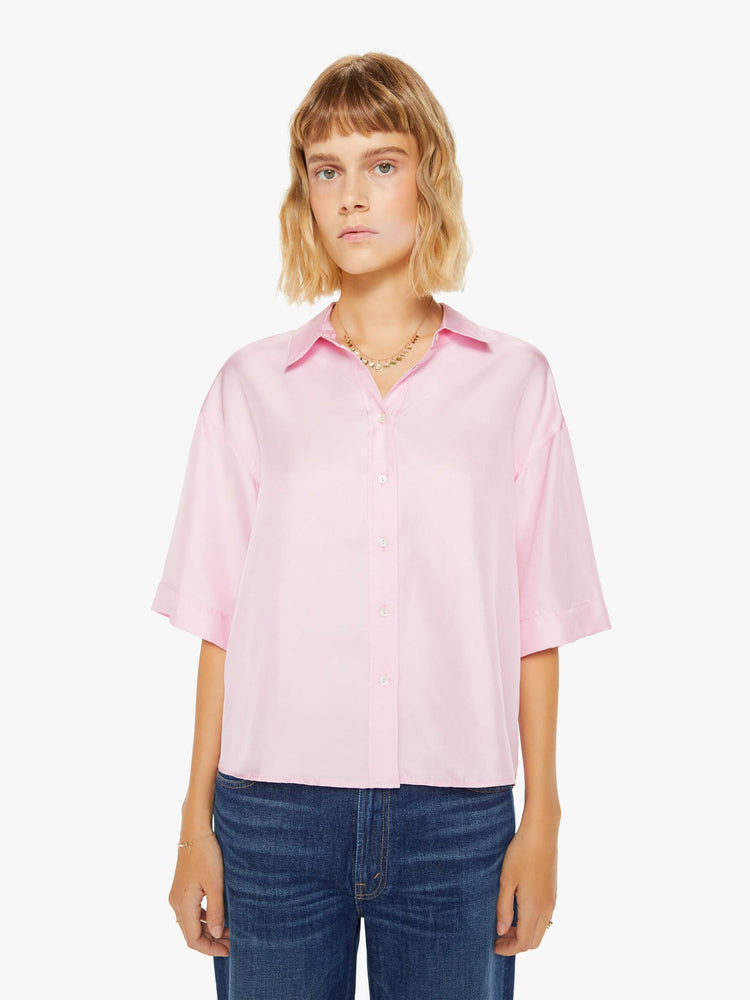 Front view of a woman pink short sleeve button-down with a collared neck, drop shoulders, oversized short sleeves and a boxy fit.