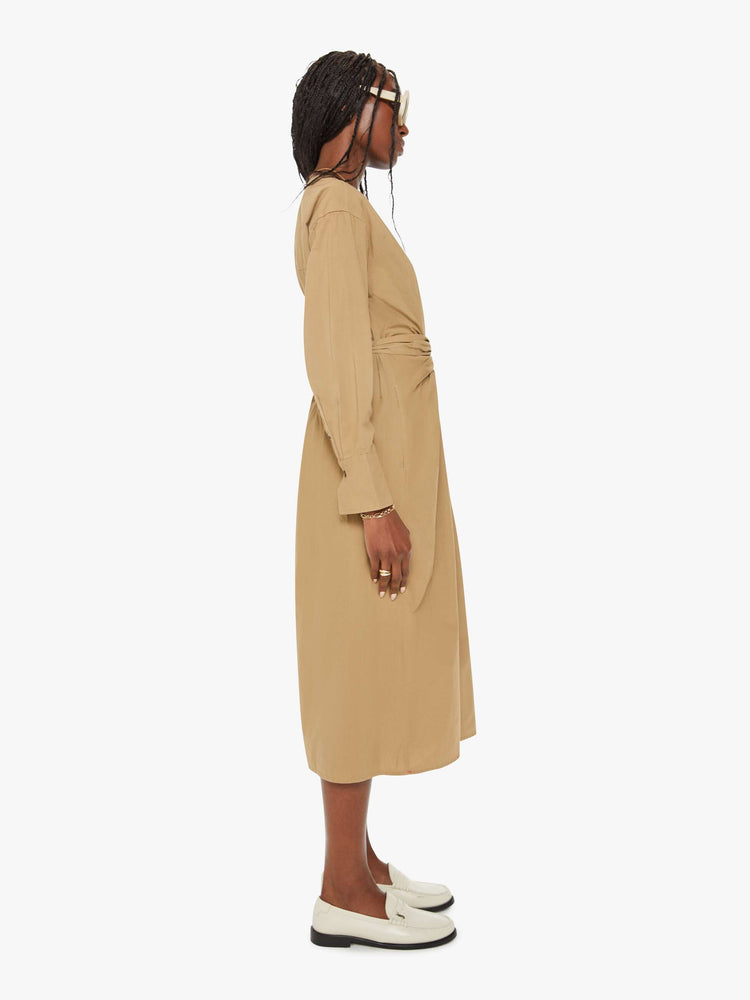 Side view of a woman dark khaki dress with a V-neck, drop shoulders, long sleeves, a tied waist, buttons down the front and a calf-length hem.