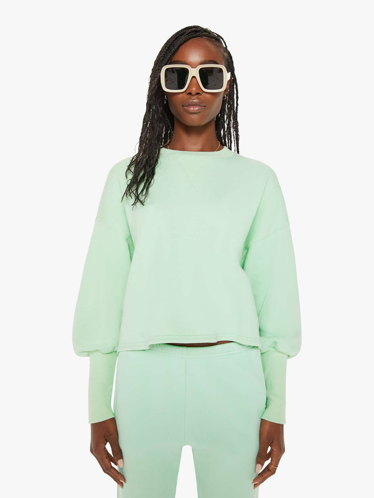 Front view of a woman minty- green hue crewneck sweatshirt with drop shoulders, bat-wing sleeves, extra-long ribbed hems at the wrists and a cropped, oversized fit.