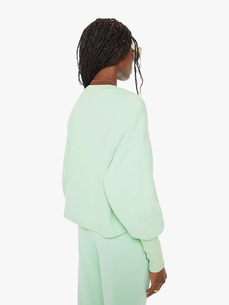 Back view of a woman minty- green hue crewneck sweatshirt with drop shoulders, bat-wing sleeves, extra-long ribbed hems at the wrists and a cropped, oversized fit.
