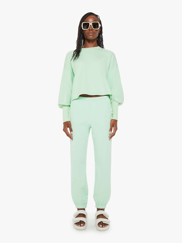Full body view of a woman minty- green hue crewneck sweatshirt with drop shoulders, bat-wing sleeves, extra-long ribbed hems at the wrists and a cropped, oversized fit.