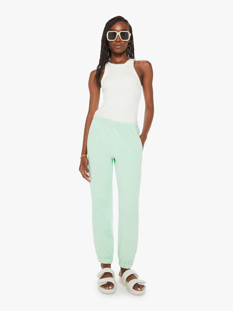 Front view of a woman mint green sweatpants with an elastic waist and hems, a high rise and a loose fit.