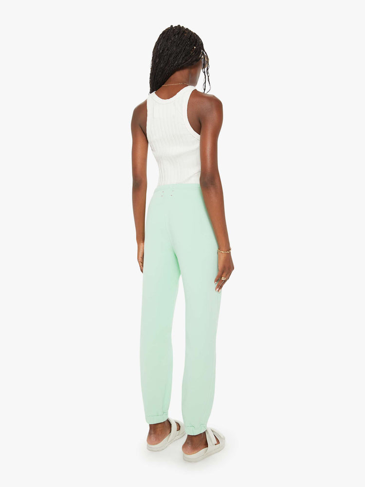 Back view of a woman mint green sweatpants with an elastic waist and hems, a high rise and a loose fit.