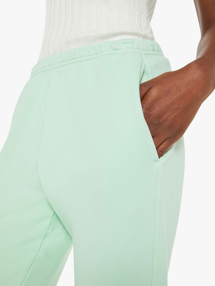 Close up view of a woman mint green sweatpants with an elastic waist and hems, a high rise and a loose fit.