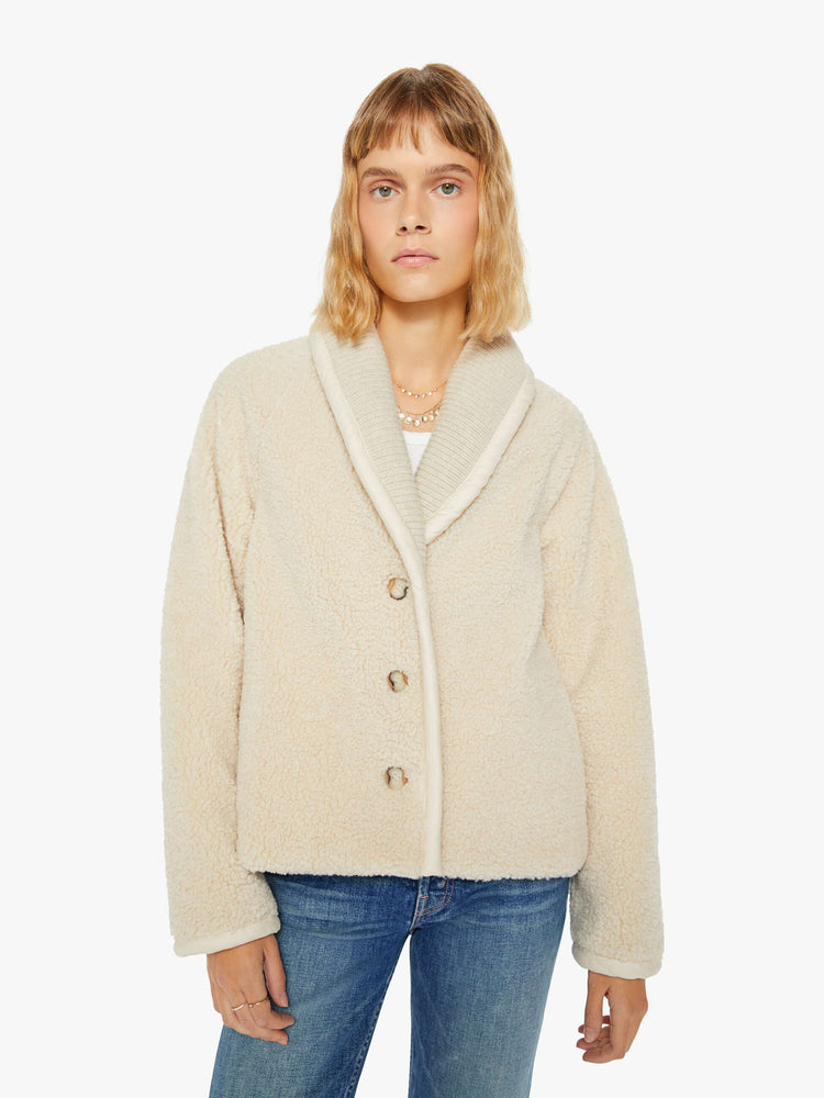 Front view of a woman jacket in a soft faux sherpa in cream with a curved collar, V-neck, slit pockets, buttons down the front, and a slightly boxy fit.