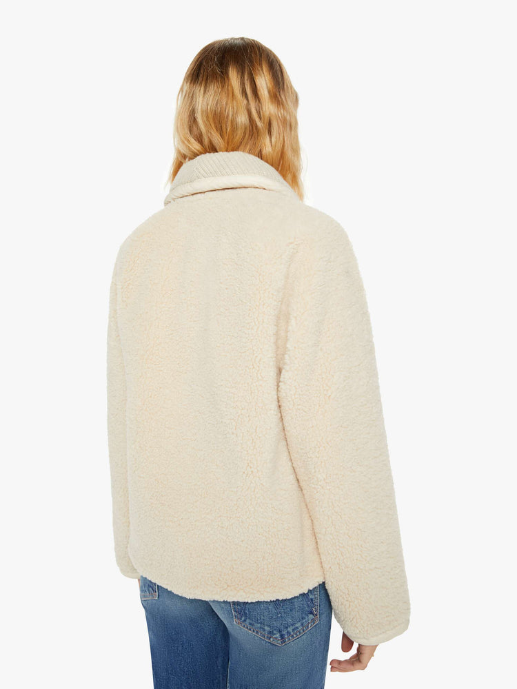 Back view of a woman jacket in a soft faux sherpa in cream with a curved collar, V-neck, slit pockets, buttons down the front, and a slightly boxy fit.