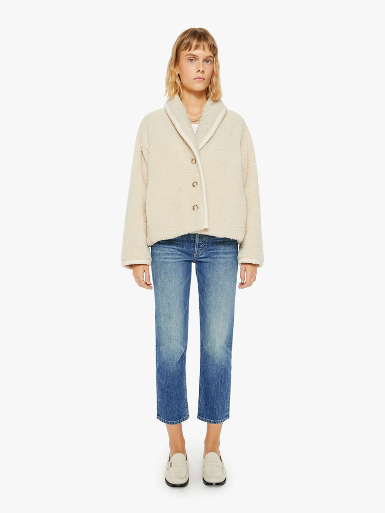 Full body view of a woman jacket in a soft faux sherpa in cream with a curved collar, V-neck, slit pockets, buttons down the front, and a slightly boxy fit.