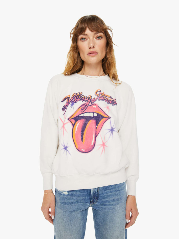 Front view of a woman white crewneck sweatshirt  pays homage to the Rolling Stones with the band's iconic tongue-and-lips logo and airbrushed details in hot pink and purple on the front.