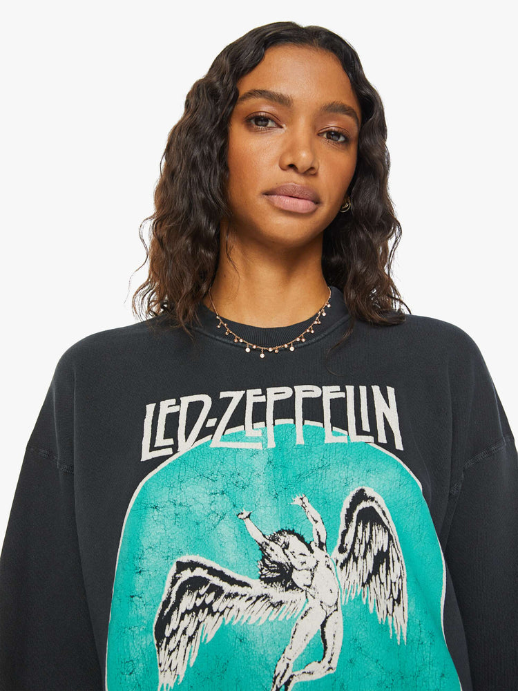 WOMEN close up view of a black sweatshirt pays homage to Led Zeppelin's 1977 tour with a faded green Icarus graphic with text in white on the front.