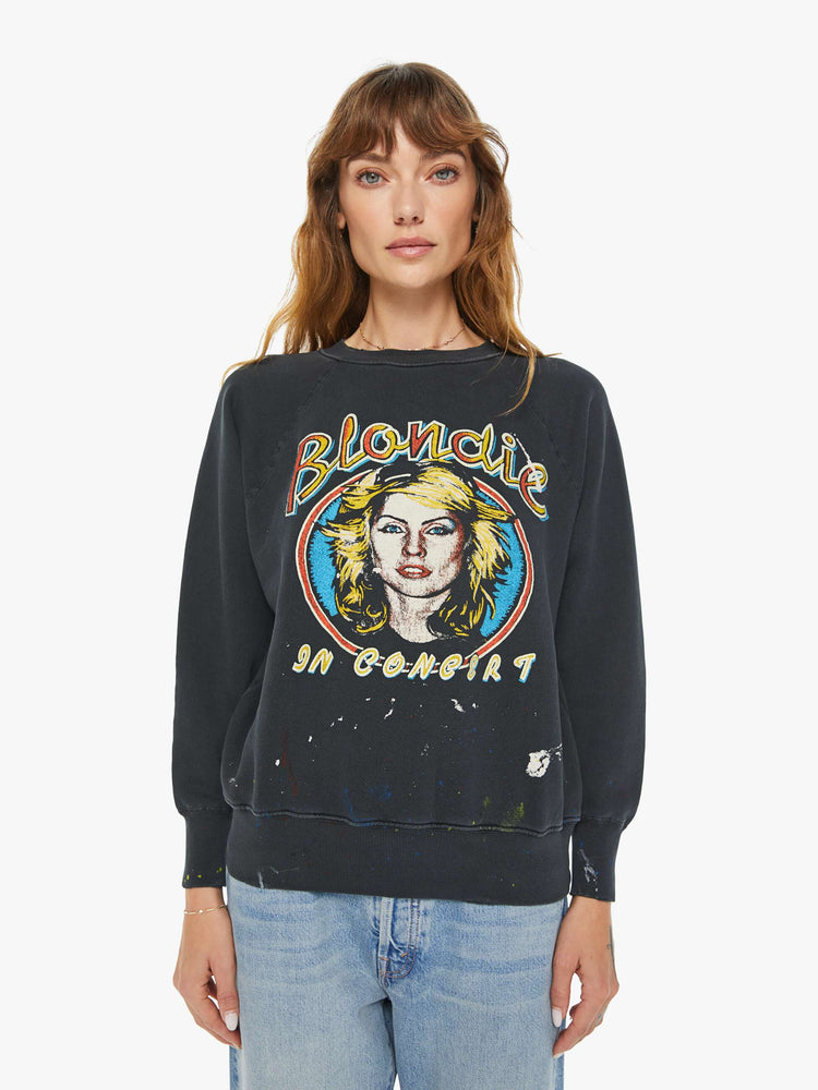 Front view of a woman black crewneck sweatshirt  pays homage to Blondie tour merch with a faded graphic portrait of the musician on the front.