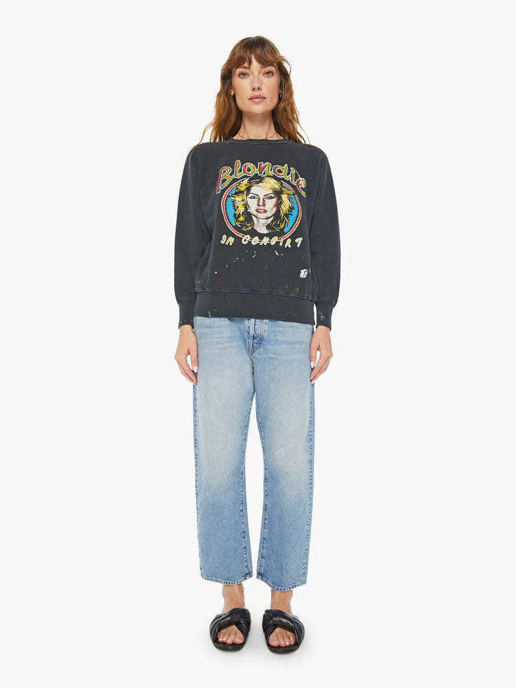 Full body view of a woman black crewneck sweatshirt pays homage to Blondie tour merch with a faded graphic portrait of the musician on the front.