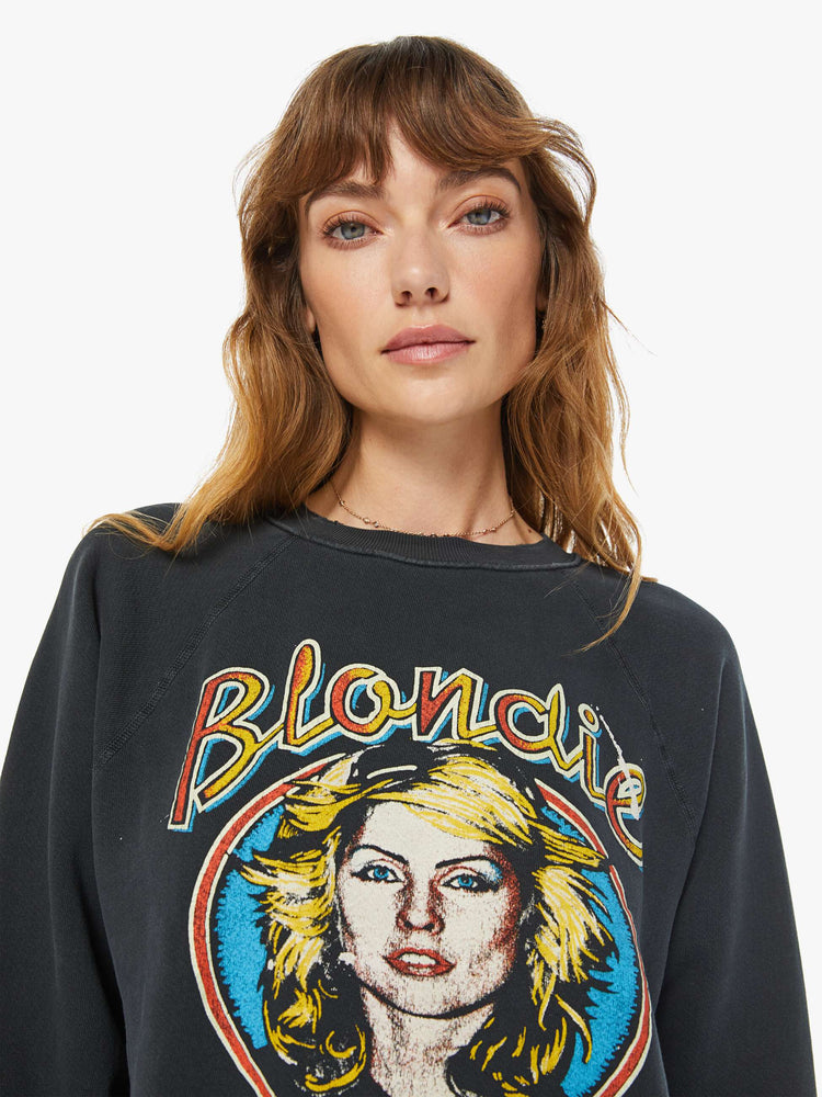 Close up view of a woman black crewneck sweatshirt pays homage to Blondie tour merch with a faded graphic portrait of the musician on the front.