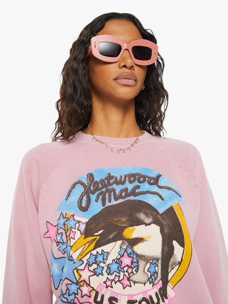 Close up view of a woman pink crewneck sweatshirt pays homage to Fleetwood Mac's U.S. tour with a colorful graphic on the front.
