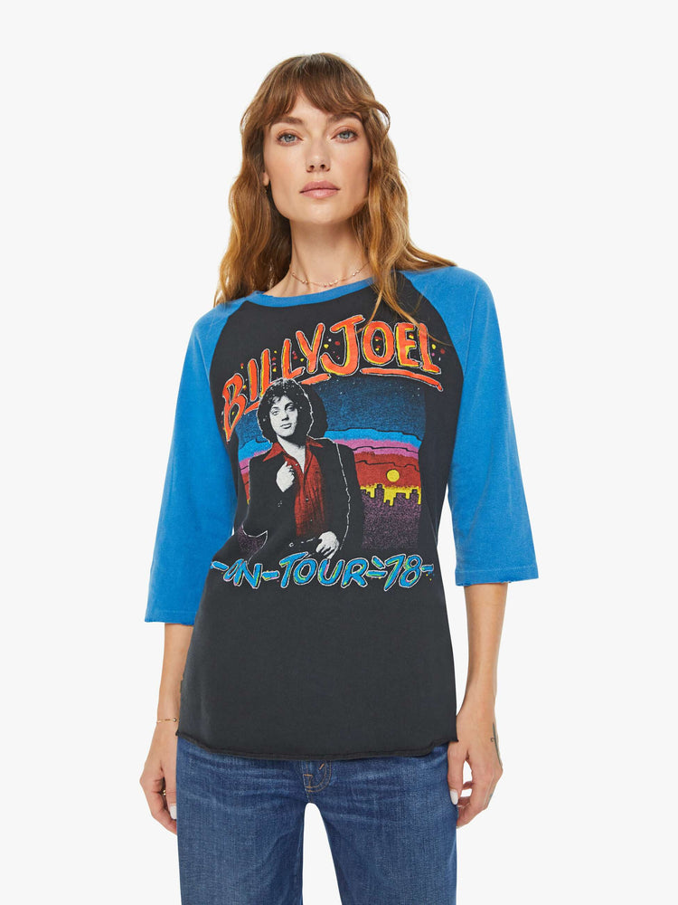 WOMEN front view of a black with a blue crewneck and sleeves tee that pays homage to Billy Joel's 1978 tour with a colorful graphic portrait on the front and a piano graphic on the back.