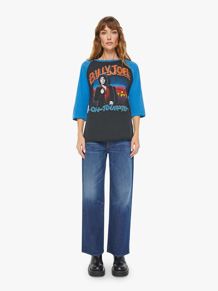 WOMEN front full body view of a black with a blue crewneck and sleeves tee that pays homage to Billy Joel's 1978 tour with a colorful graphic portrait on the front and a piano graphic on the back.