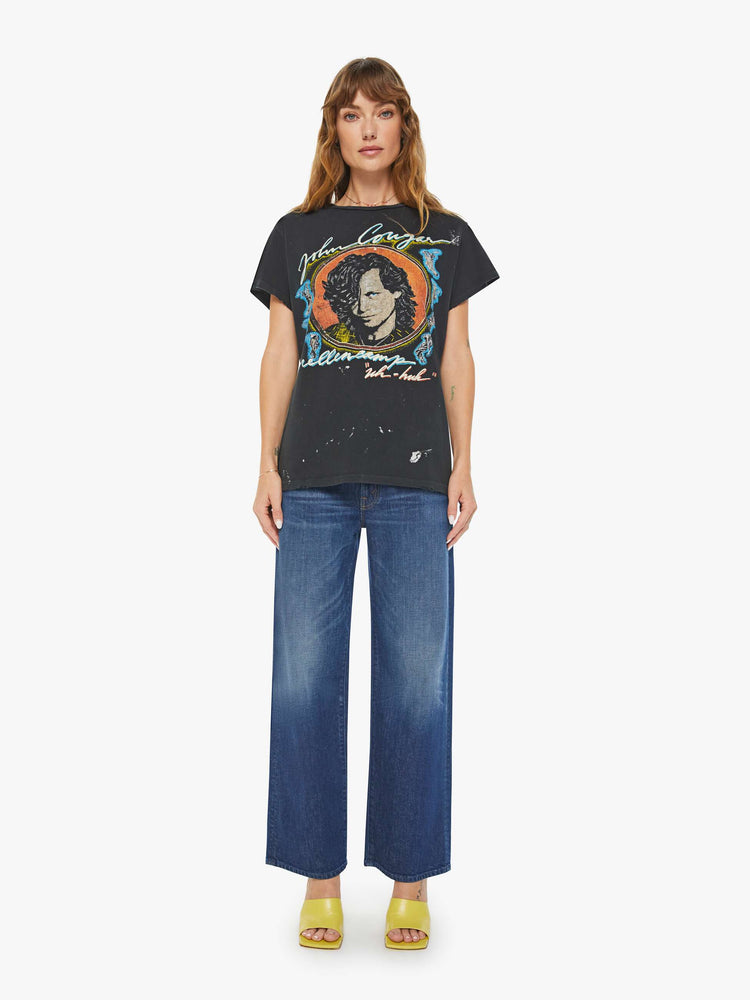 Full body view of women black tee honors John Cougar Mellencamp with a faded graphic portrait on the front.