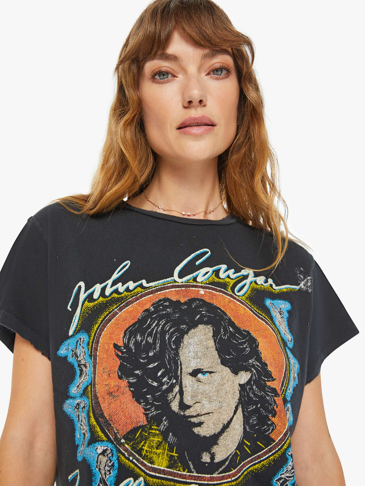 Close up view of women black tee honors John Cougar Mellencamp with a faded graphic portrait on the front.