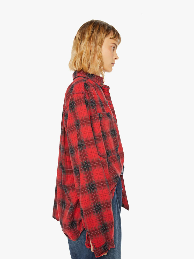 Side view of a woman red and black plaid shirt features front patch pockets, buttons down the front and a boxy, oversized fit.