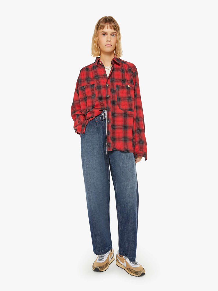 Full body view of a woman red and black plaid shirt features front patch pockets, buttons down the front and a boxy, oversized fit.
