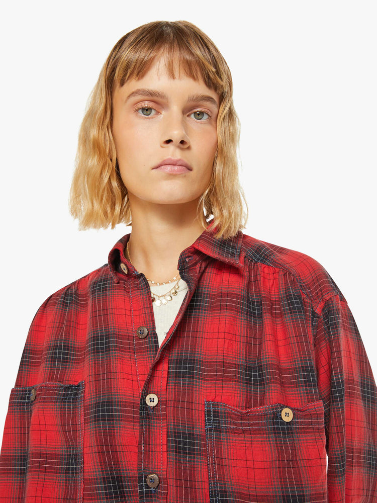 Close up view of a woman red and black plaid shirt features front patch pockets, buttons down the front and a boxy, oversized fit.