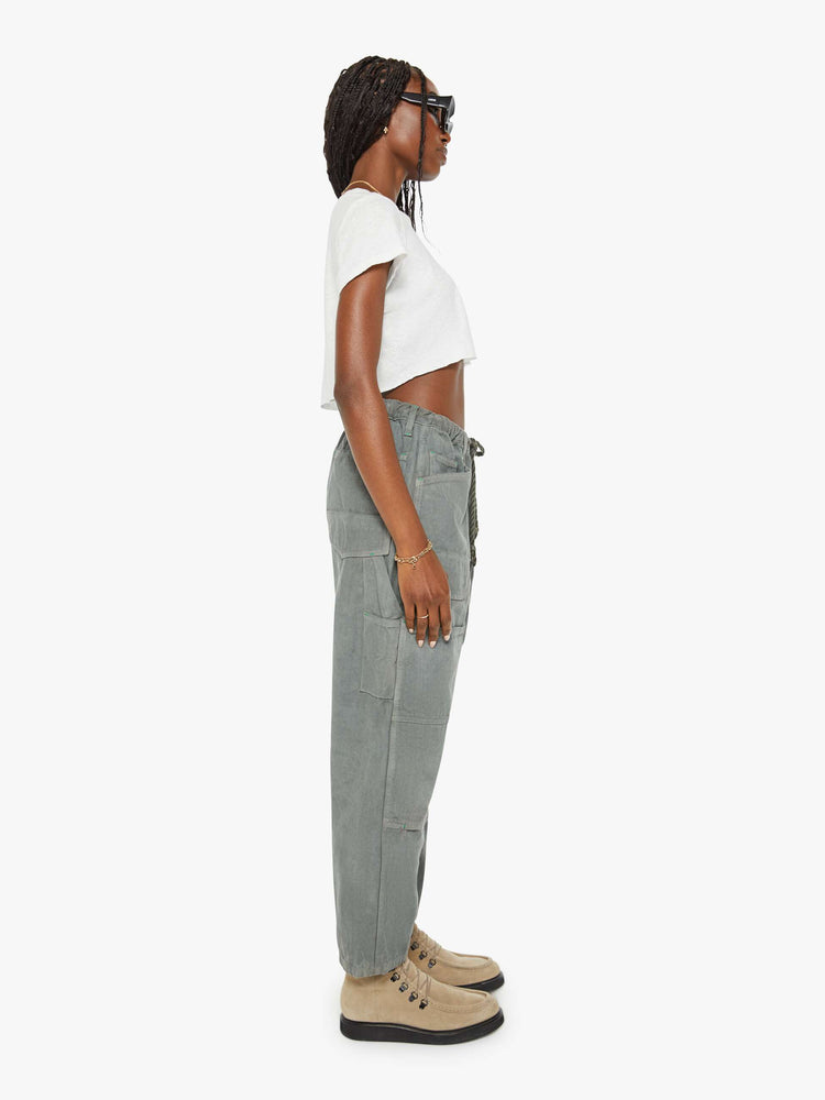 Side view of a woman army green hue cargo pant with a mid rise, narrow straight leg and oversized patch pockets throughout.