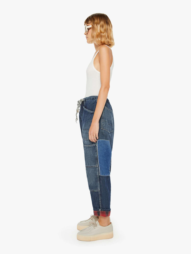 Left side view of a woman sunfaded dark wash cargo pants with a mid rise, narrow straight leg and oversized patch pockets throughout.