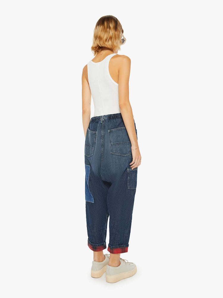 Back view of a woman sunfaded dark wash cargo pants with a mid rise, narrow straight leg and oversized patch pockets throughout.