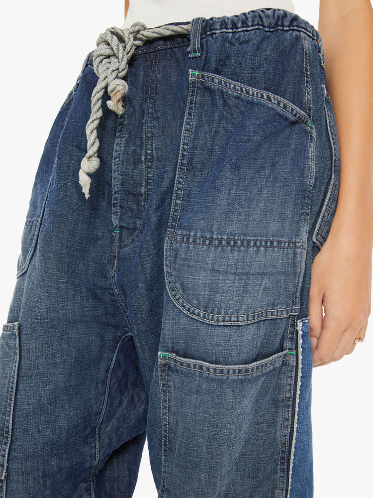 Waist close up view of a woman sunfaded dark wash cargo pants with a mid rise, narrow straight leg and oversized patch pockets throughout.