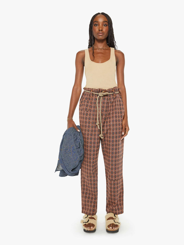 Front view of a woman farmer pant in an orange and brown print with a high rise, straight leg, drawstring waist, a slightly cropped inseam and a loose fit.
